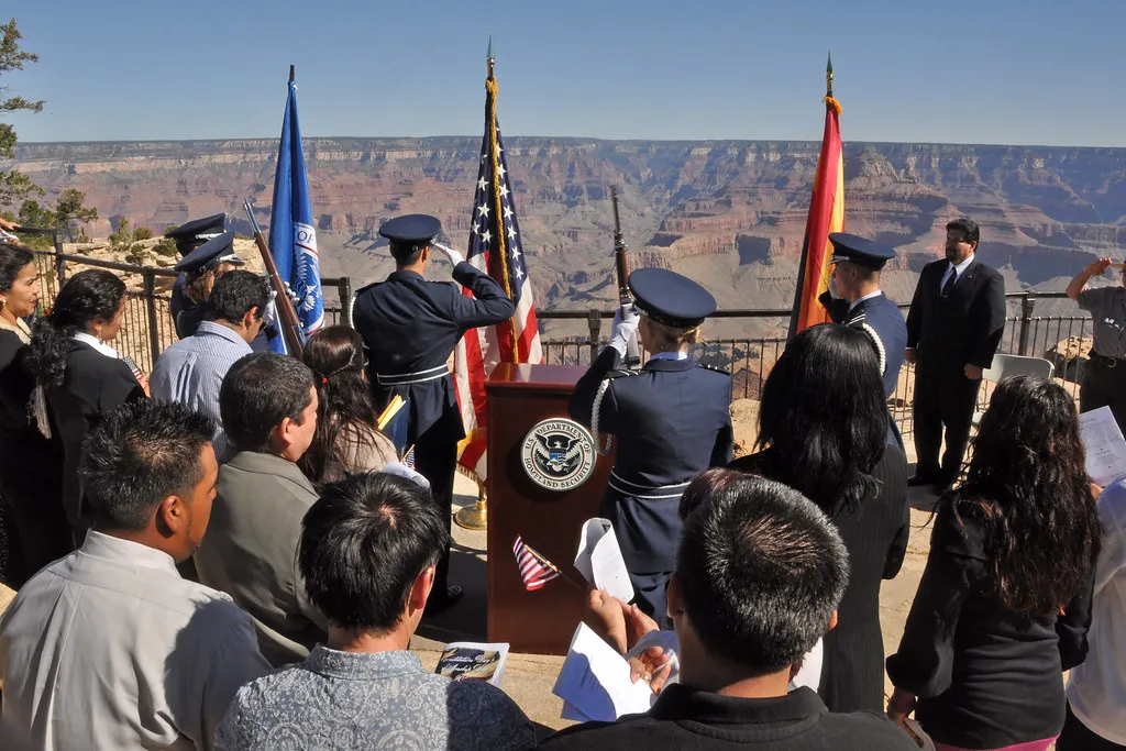 New American citizens at a U.S. naturalization ceremony with American flag and military honor guard