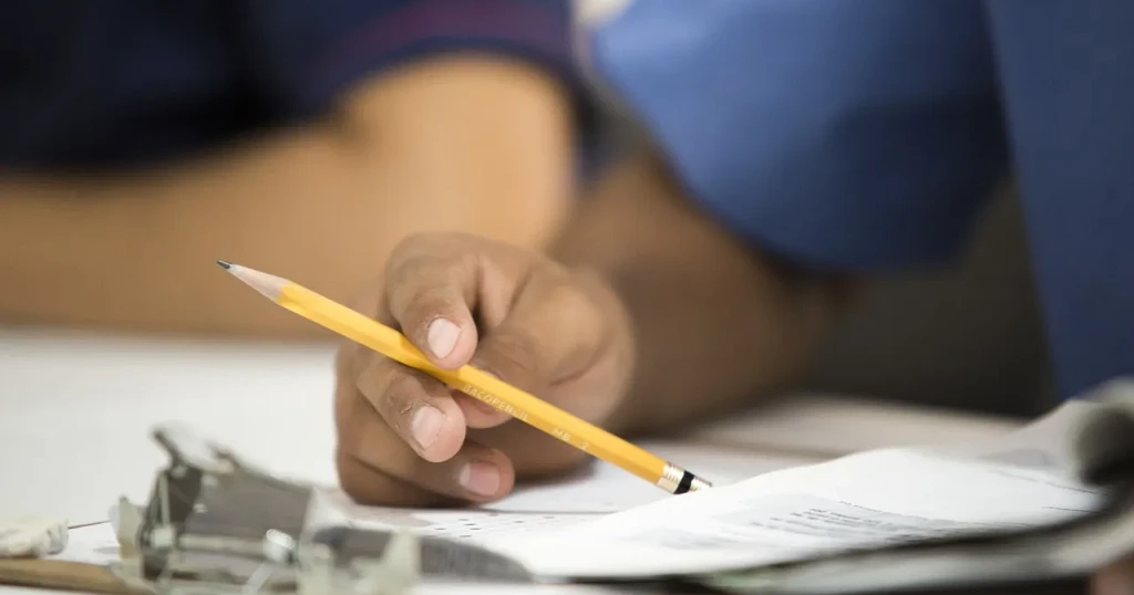 Hand holding a pencil over a printed form on a clipboard