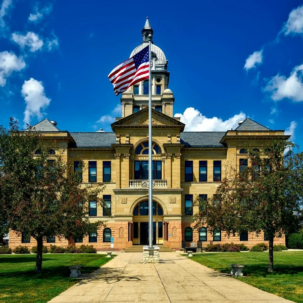 Historic domed courthouse behind an American flag flying on a tall flagpole